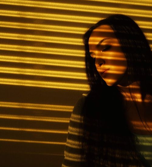 Woman in a peaceful yoga pose in a dark room with golden light.